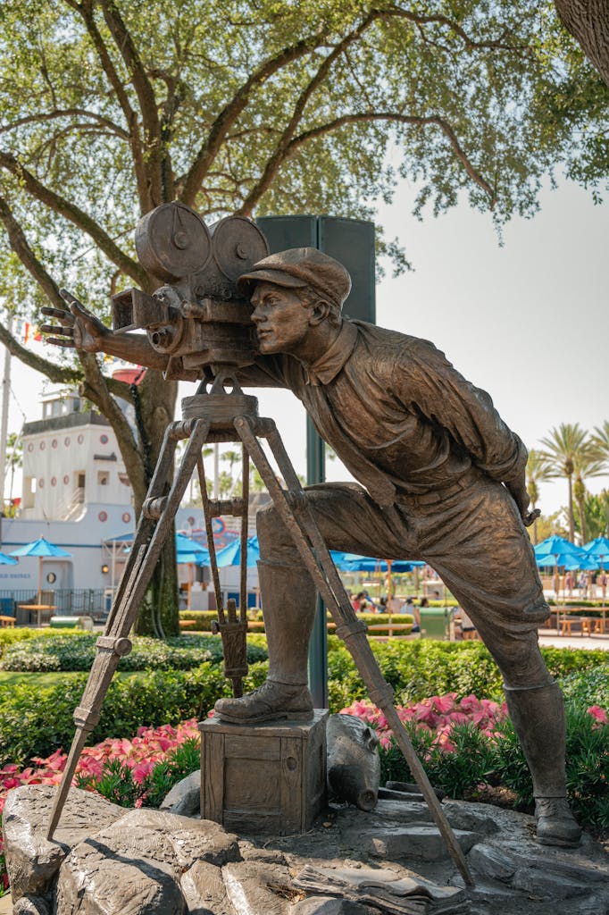 Bronze cameraman sculpture in a garden at a popular film-themed park.